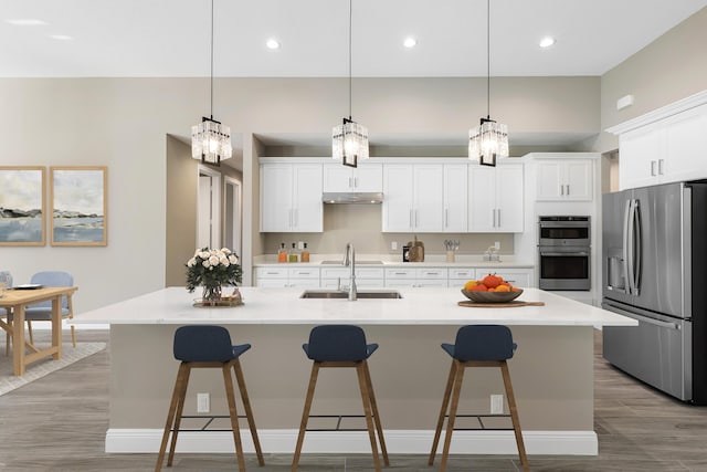 kitchen featuring stainless steel appliances, light countertops, decorative light fixtures, and a large island with sink