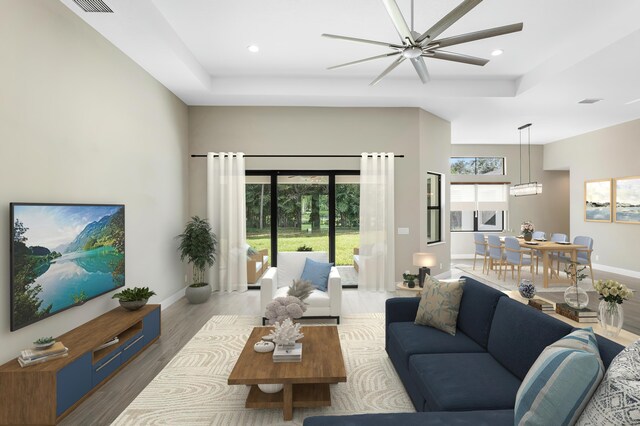 living room with ceiling fan, a raised ceiling, and light hardwood / wood-style flooring