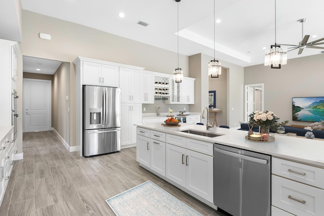 kitchen with stainless steel appliances, a sink, white cabinetry, light countertops, and pendant lighting