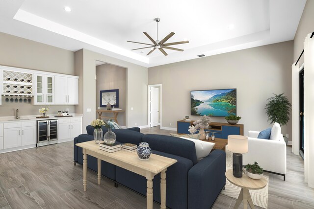 living room with hardwood / wood-style floors, ceiling fan, and a raised ceiling