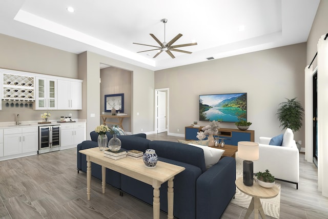 living area with light wood finished floors, beverage cooler, baseboards, wet bar, and a tray ceiling