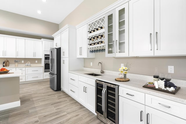 kitchen with beverage cooler, glass insert cabinets, freestanding refrigerator, white cabinetry, and a sink