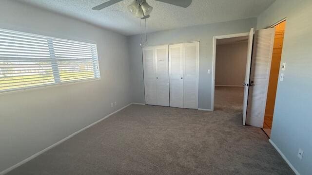 unfurnished bedroom with carpet flooring, ceiling fan, a closet, and a textured ceiling