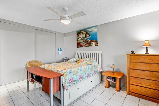 bedroom with light tile patterned floors, a textured ceiling, a closet, and ceiling fan