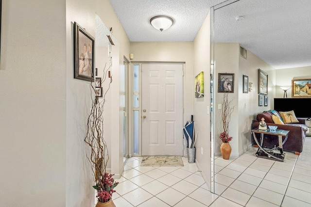 foyer entrance with light tile patterned flooring and a textured ceiling