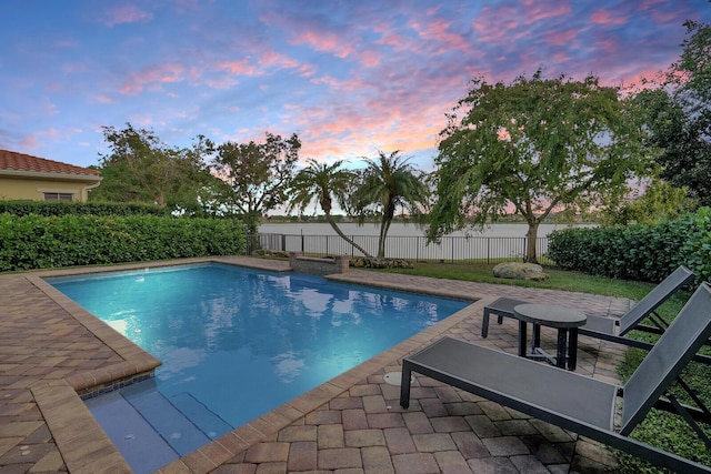 pool at dusk featuring a patio