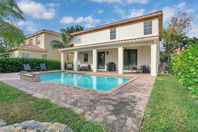 rear view of house featuring ceiling fan, a fenced in pool, and a patio