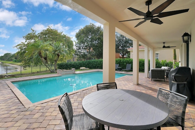 view of swimming pool with a grill, ceiling fan, a water view, and a patio