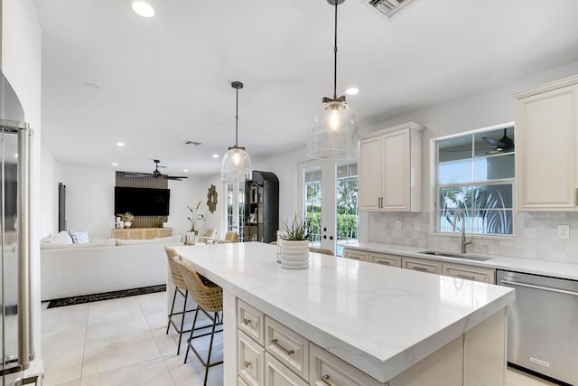 kitchen featuring ceiling fan, a center island, sink, hanging light fixtures, and stainless steel dishwasher