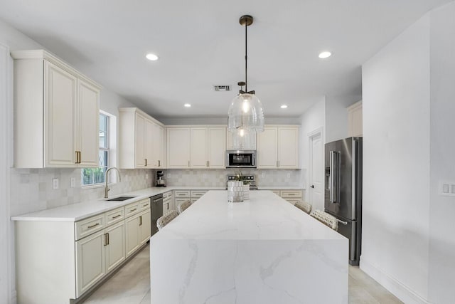 kitchen with light stone countertops, stainless steel appliances, sink, a center island, and hanging light fixtures