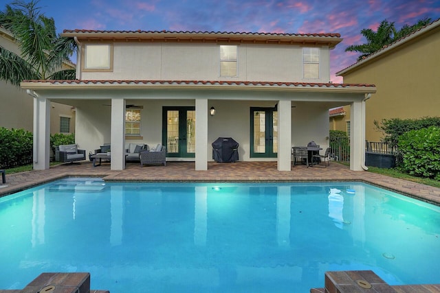 back house at dusk featuring french doors, an outdoor hangout area, and a patio