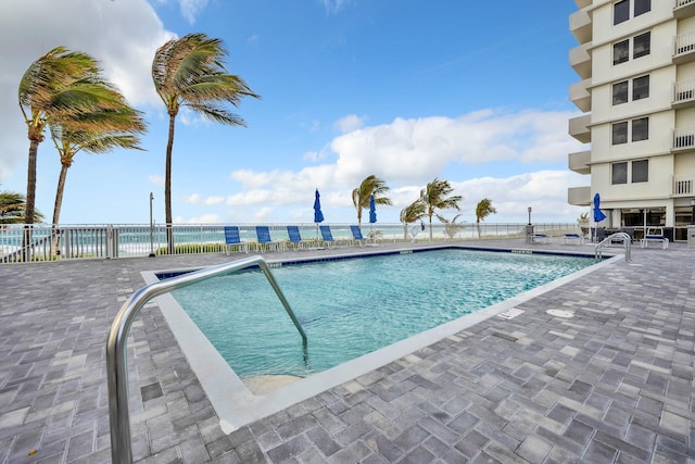 view of pool featuring a patio and a water view