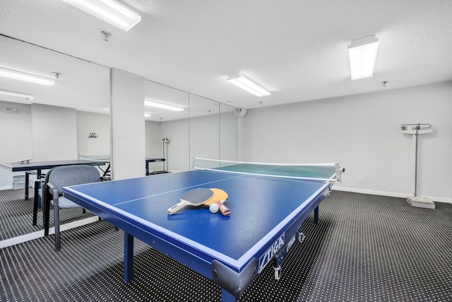 playroom featuring dark colored carpet and a textured ceiling