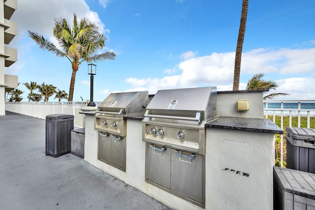 view of patio / terrace featuring a water view, area for grilling, and exterior kitchen