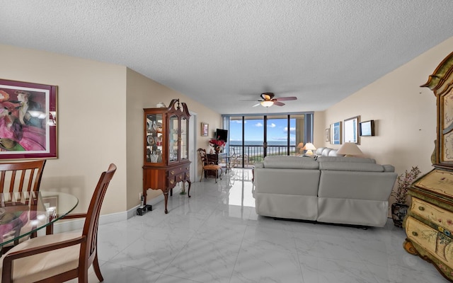 living room featuring ceiling fan, floor to ceiling windows, and a textured ceiling