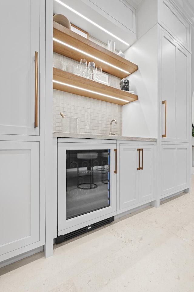 bar featuring wine cooler, decorative backsplash, sink, and white cabinets