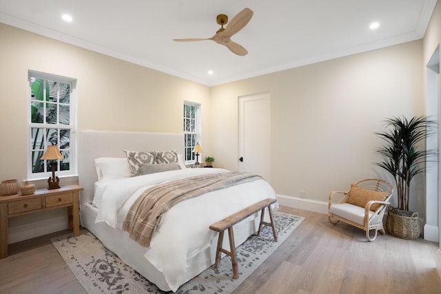 bedroom with multiple windows, light hardwood / wood-style floors, ceiling fan, and ornamental molding