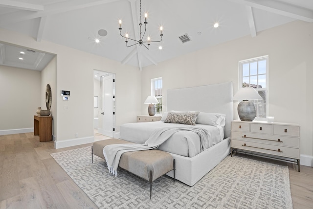 bedroom featuring lofted ceiling with beams, light hardwood / wood-style floors, connected bathroom, and a chandelier