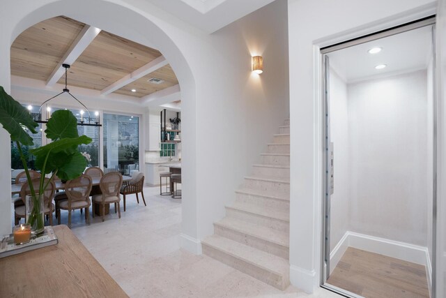 living room with beamed ceiling, a notable chandelier, wooden ceiling, and a high end fireplace