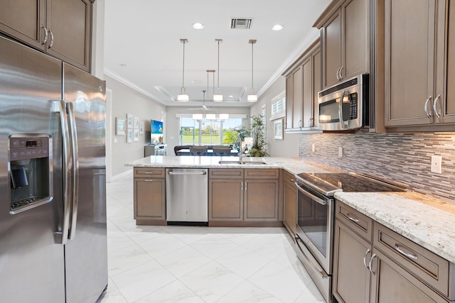 kitchen featuring kitchen peninsula, ornamental molding, pendant lighting, and appliances with stainless steel finishes