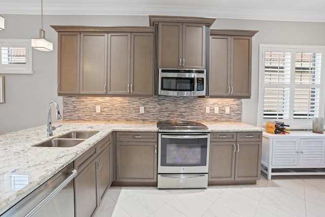 kitchen featuring tasteful backsplash, ornamental molding, stainless steel appliances, sink, and decorative light fixtures