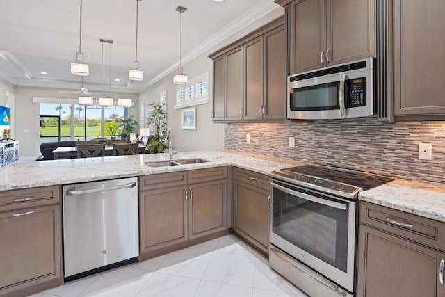 kitchen with sink, stainless steel appliances, kitchen peninsula, pendant lighting, and ornamental molding