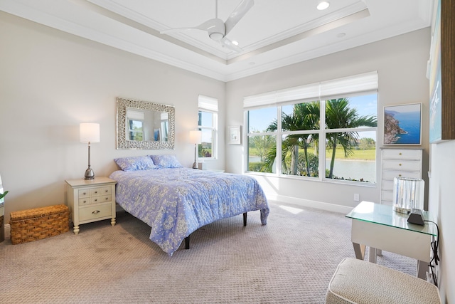 bedroom featuring light carpet, a raised ceiling, ceiling fan, crown molding, and a water view