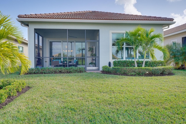 rear view of house featuring a sunroom and a lawn