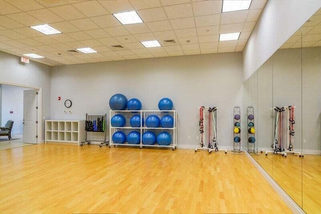 workout area featuring a drop ceiling, a towering ceiling, and hardwood / wood-style flooring