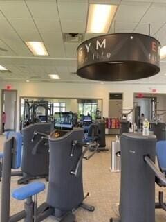 workout area featuring a paneled ceiling, carpet flooring, and electric water heater