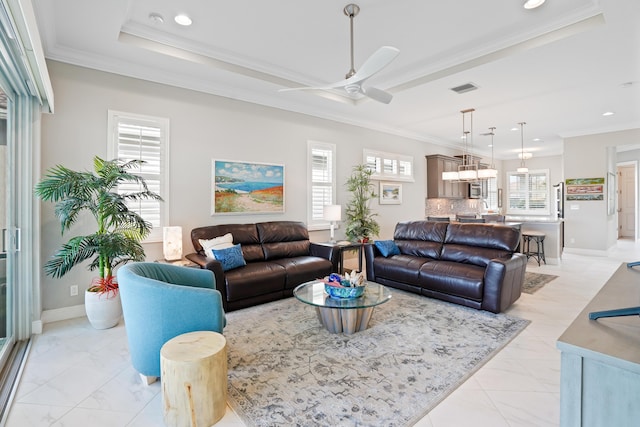 living room featuring plenty of natural light, ceiling fan, ornamental molding, and a tray ceiling