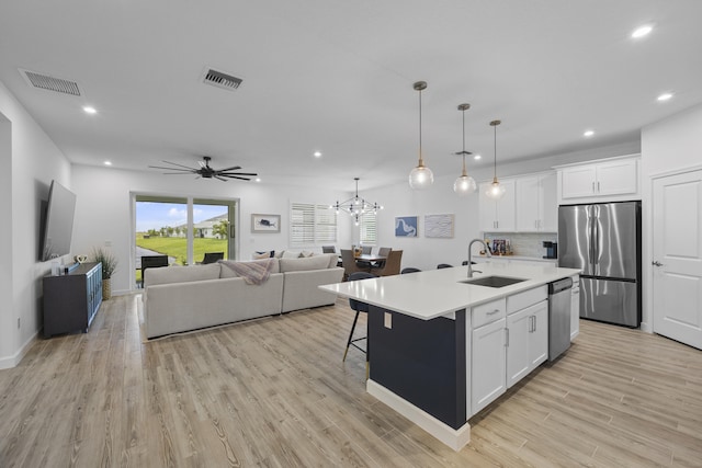 kitchen with stainless steel appliances, a kitchen island with sink, sink, and white cabinets