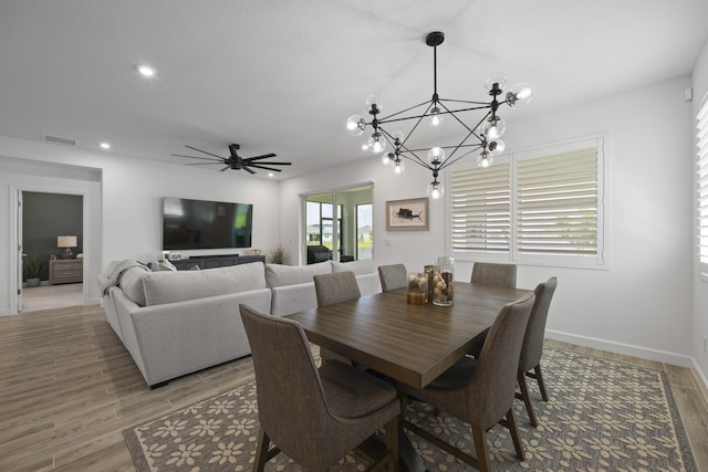 dining area featuring ceiling fan with notable chandelier and wood-type flooring