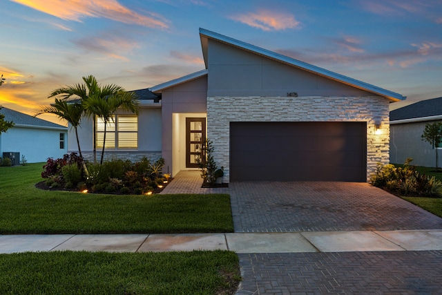 view of front facade featuring a garage, a lawn, and central AC