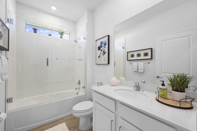 full bathroom featuring vanity, hardwood / wood-style floors, toilet, and combined bath / shower with glass door