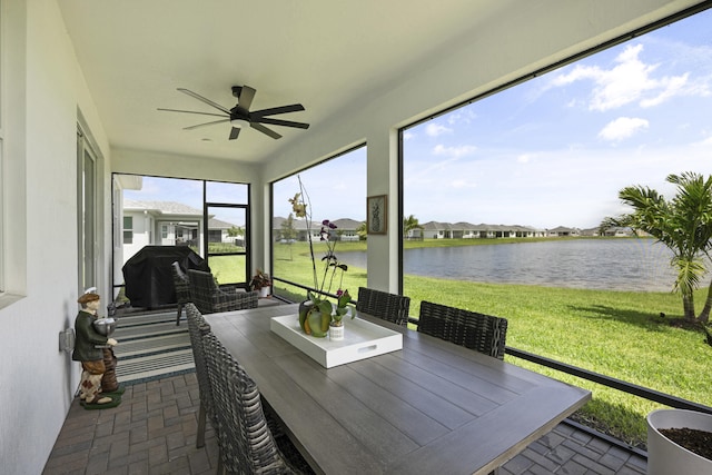 sunroom / solarium featuring a water view and ceiling fan