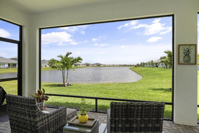 sunroom featuring a water view