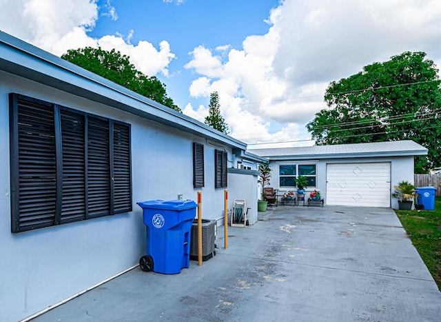 view of side of home featuring central AC unit, a garage, and an outbuilding