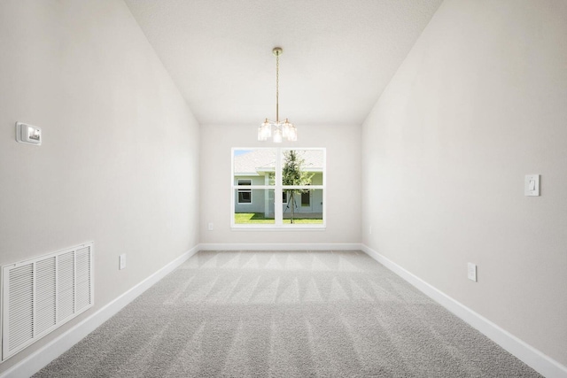 carpeted empty room featuring a chandelier