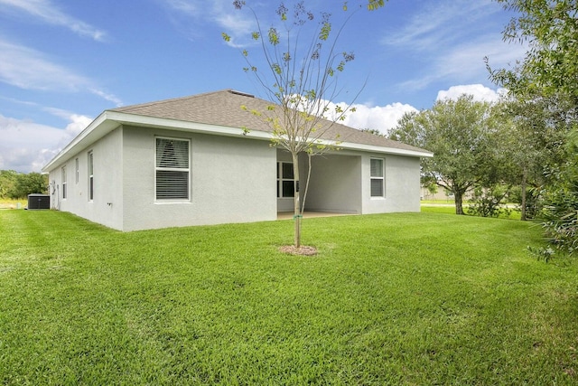 rear view of property featuring central AC and a lawn