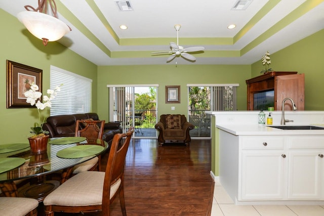 kitchen with a raised ceiling, sink, ceiling fan, dark hardwood / wood-style flooring, and white cabinetry