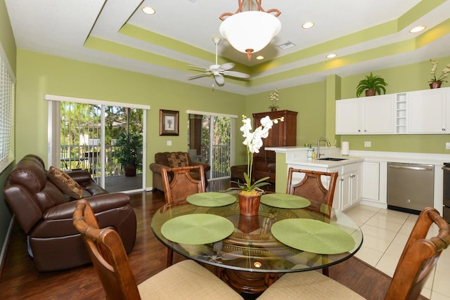 tiled dining area with a tray ceiling, ceiling fan, and sink