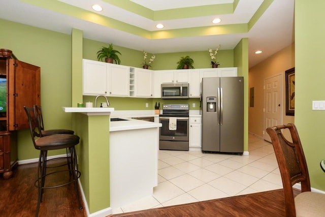 kitchen with stainless steel appliances, light hardwood / wood-style flooring, kitchen peninsula, a breakfast bar area, and white cabinets