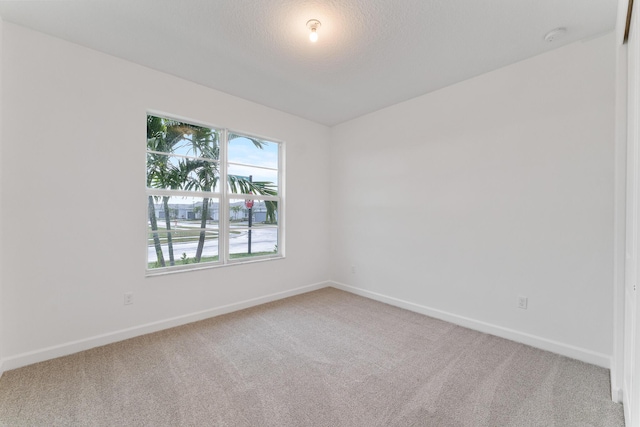 carpeted empty room with baseboards and a textured ceiling