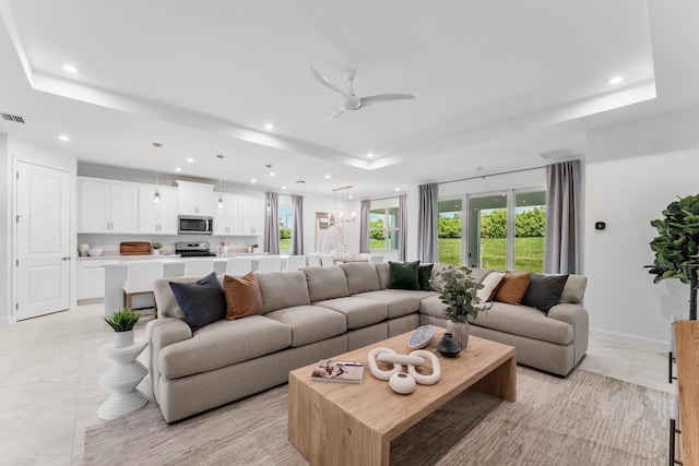 living room with recessed lighting, a tray ceiling, marble finish floor, and visible vents