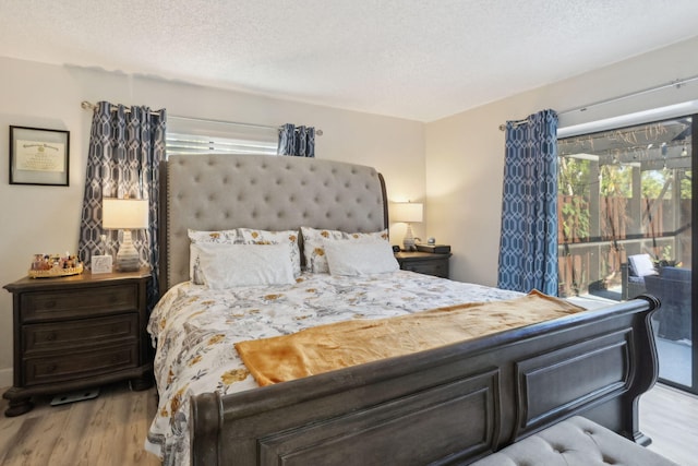 bedroom featuring a textured ceiling, light wood-type flooring, and access to outside