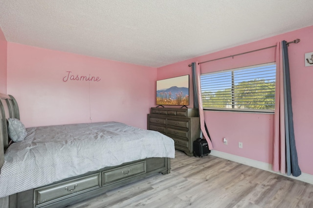 bedroom with a textured ceiling and light wood-type flooring