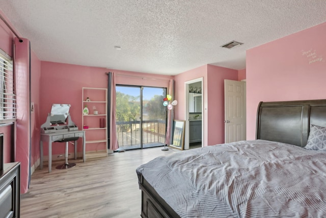 bedroom with light hardwood / wood-style floors, a textured ceiling, access to outside, and ensuite bath