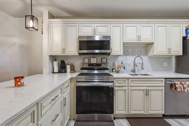 kitchen with light stone countertops, sink, stainless steel appliances, pendant lighting, and decorative backsplash