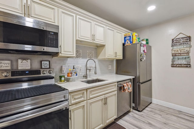 kitchen with cream cabinetry, appliances with stainless steel finishes, light wood-type flooring, and sink